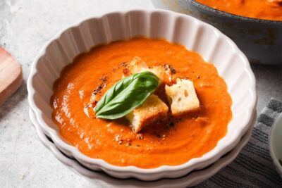 Fire-roasted tomato soup in a bowl garnished with basil and croutons