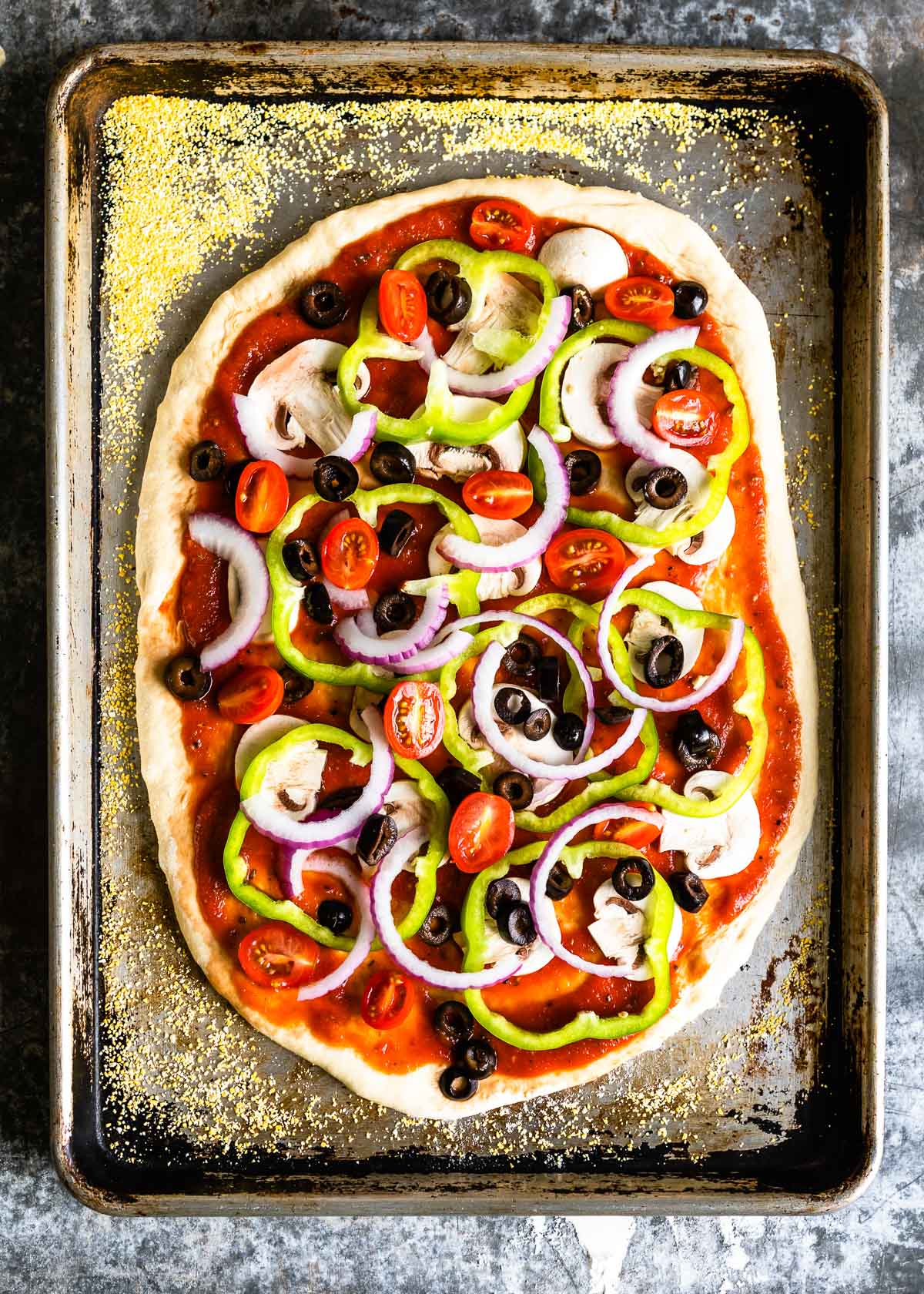 Fresh vegetable toppings on a  rolled-out pizza dough