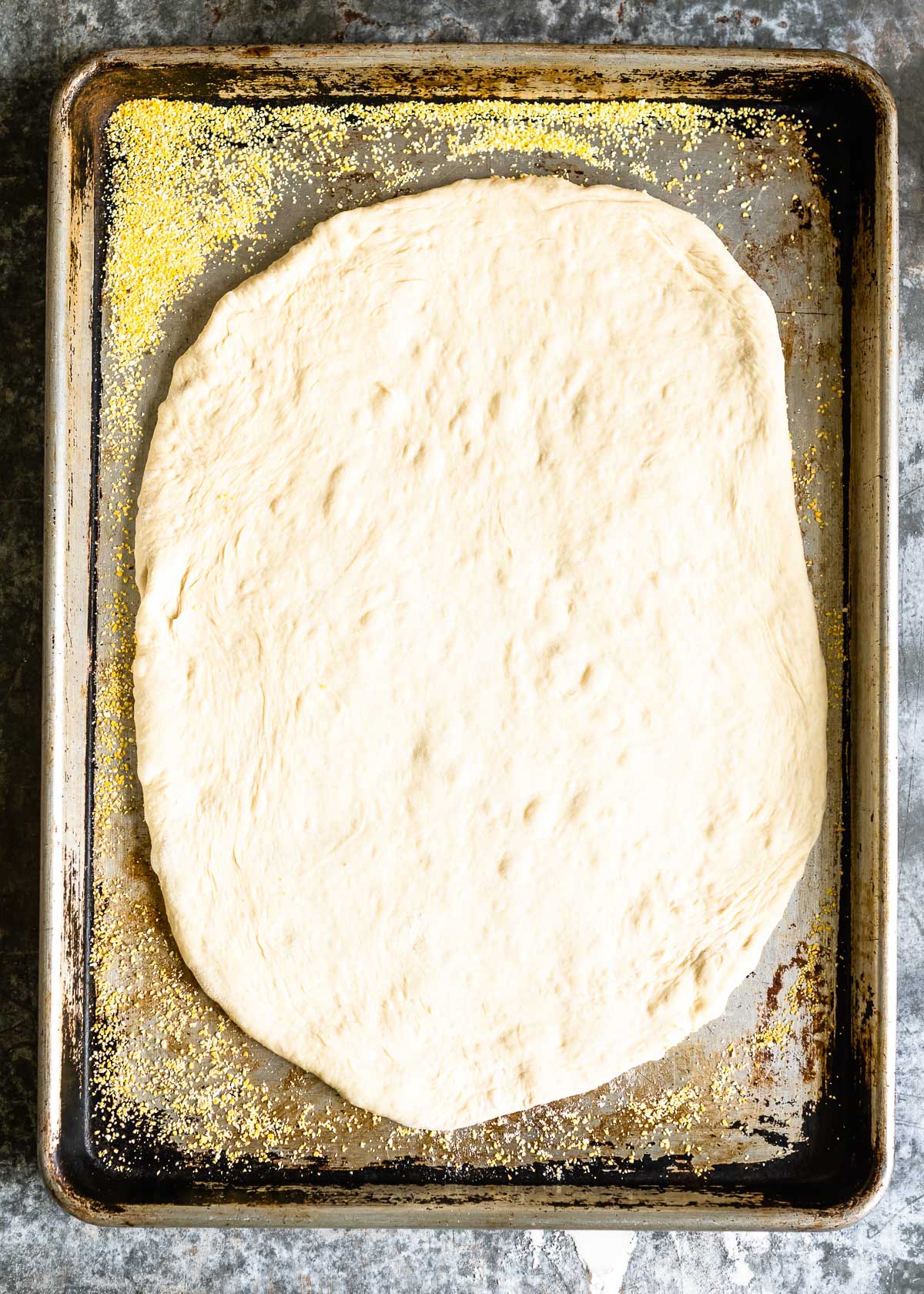 Uncooked pizza dough rolled out on a baking tray