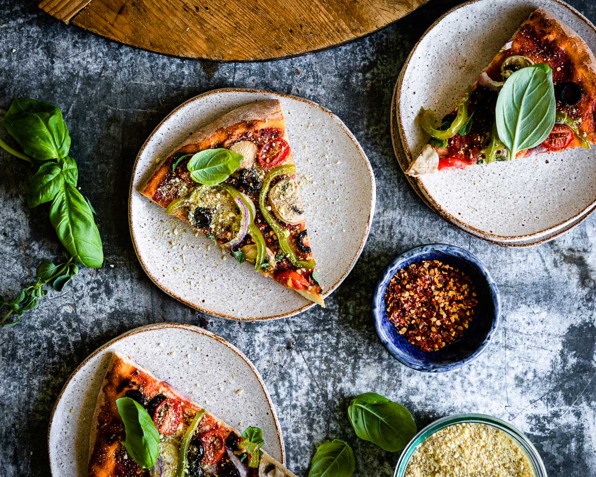 Three slices of vegan pizza placed on plates ready for serving