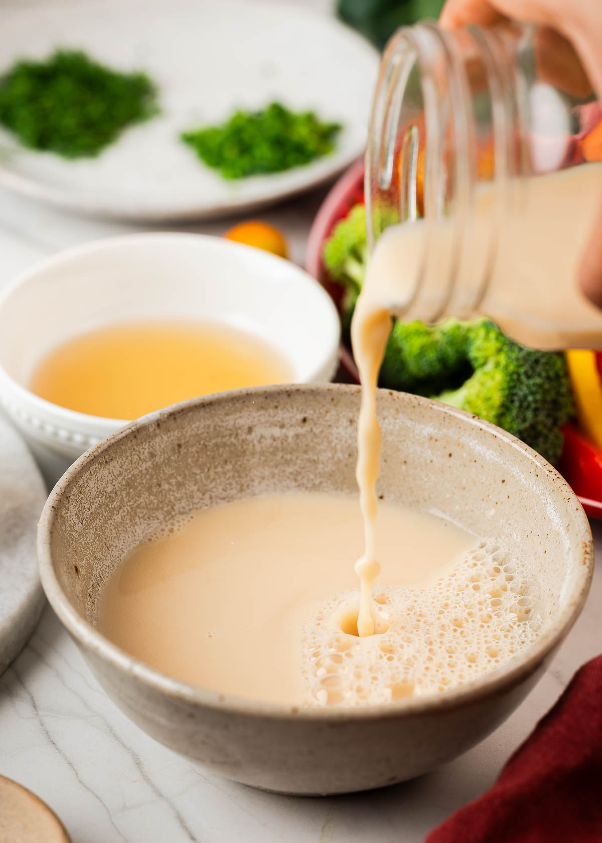 A jar of cashew milk being poured into a bowl.