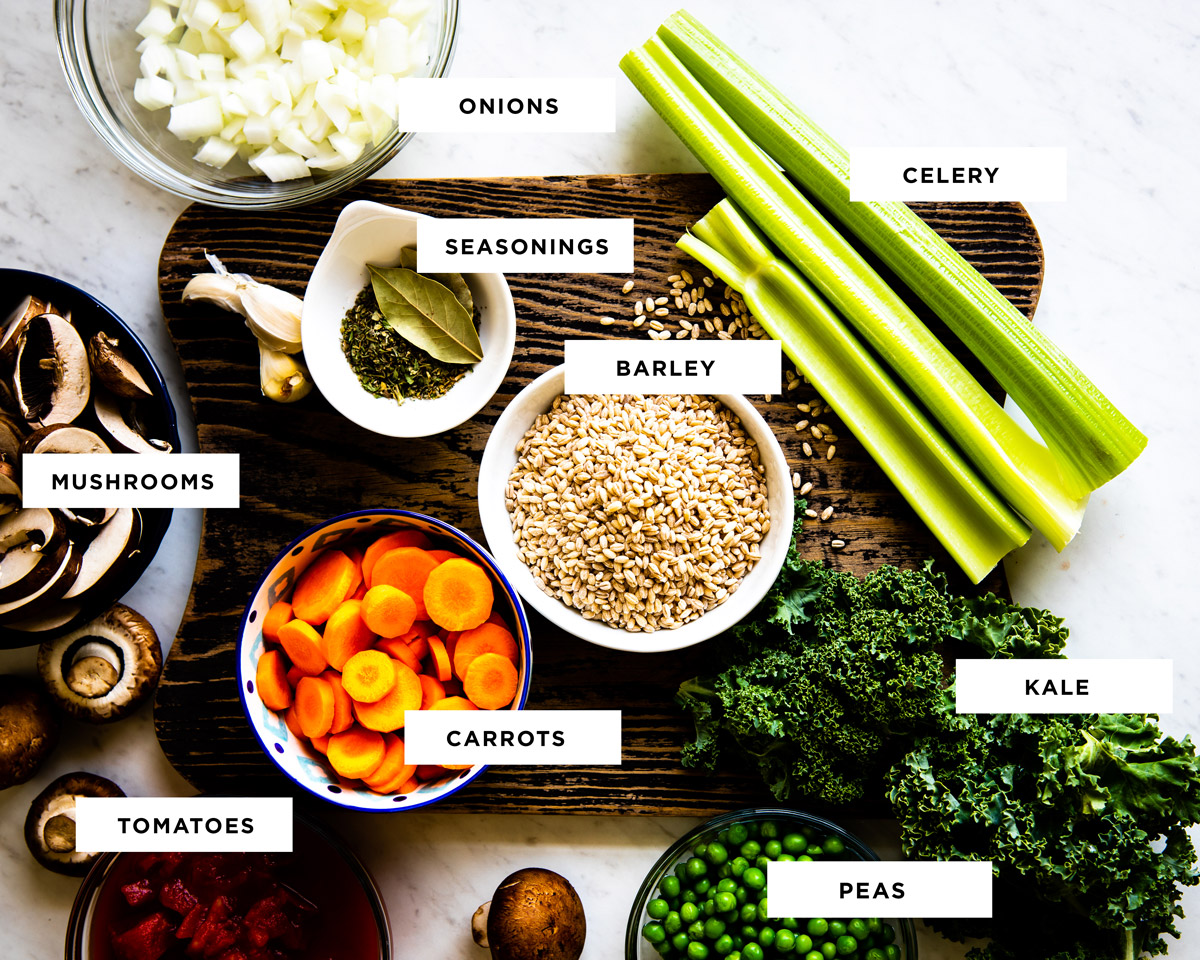 Fresh vegetables on a walnut cutting board on a quartz-white countertop.