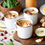 Three white mugs of warm wassail drink.