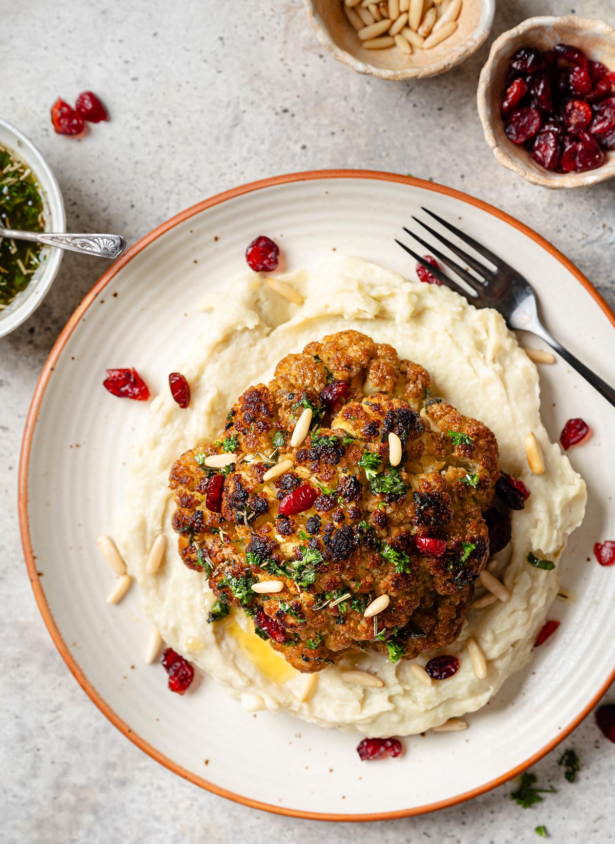 Close up of whole roasted cauliflower with toasted pine nuts and cranberries