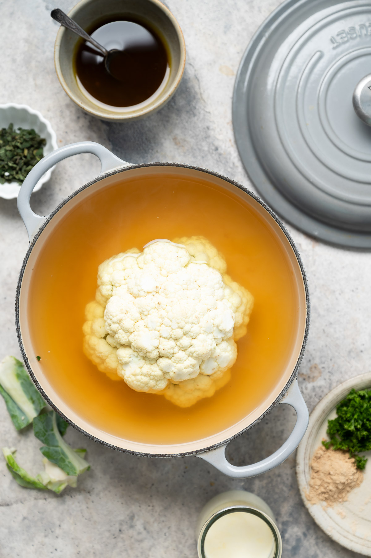 A head of cauliflower in vegetable broth being blanched for tenderness
