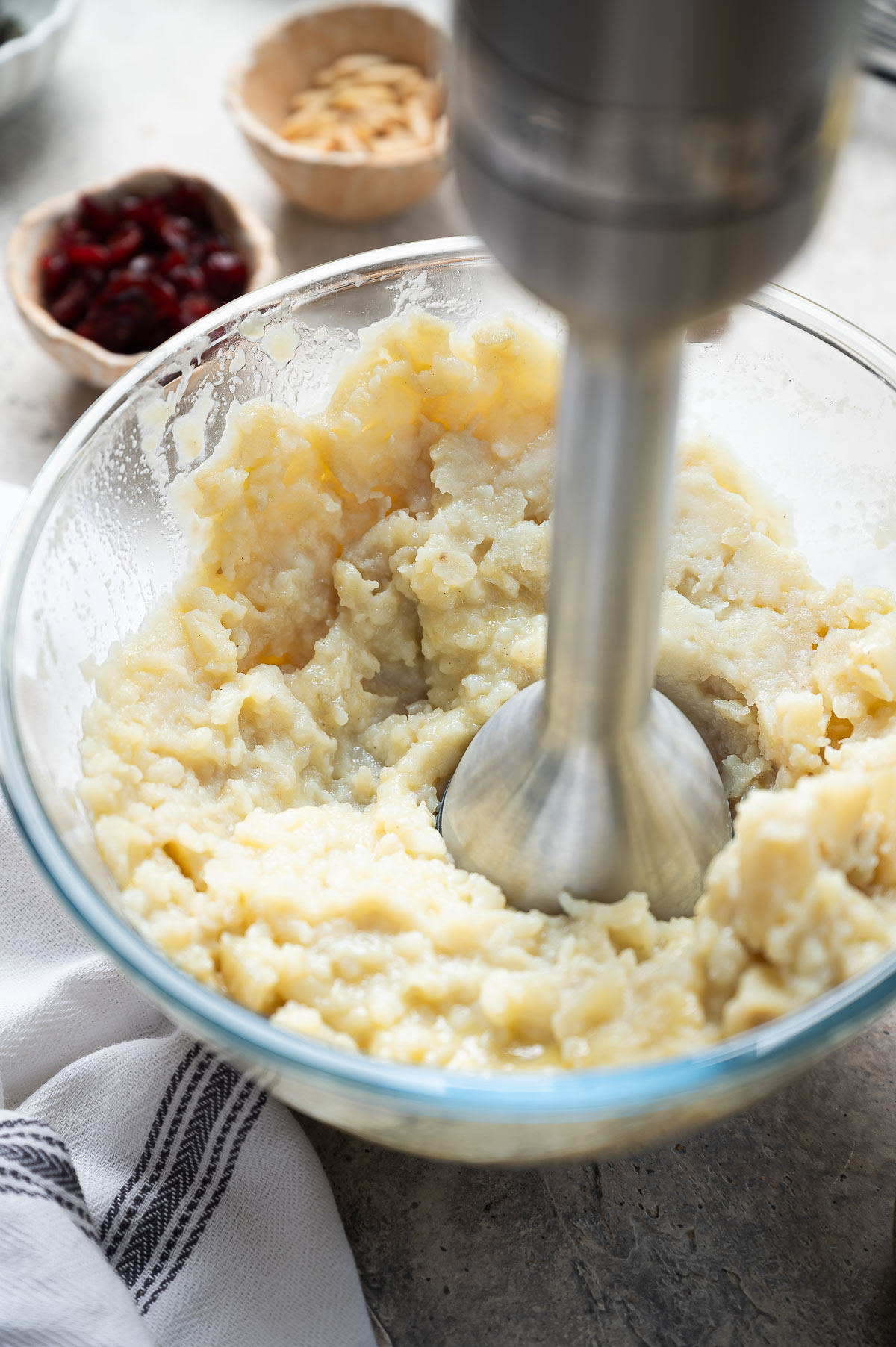 Potatoes In a glass bowl being mashed with an immersion blender