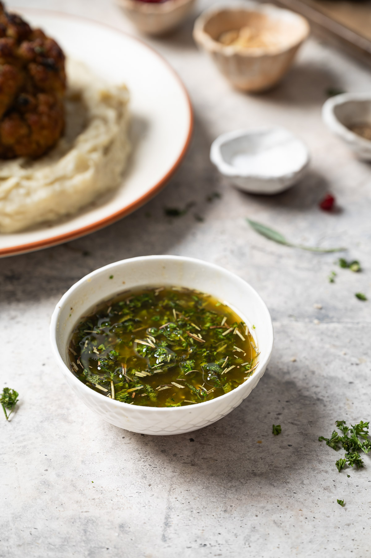 A small white bowl filled with rustic herb sauce