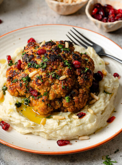 A whole roasted cauliflower head on a bed of mashed potatoes