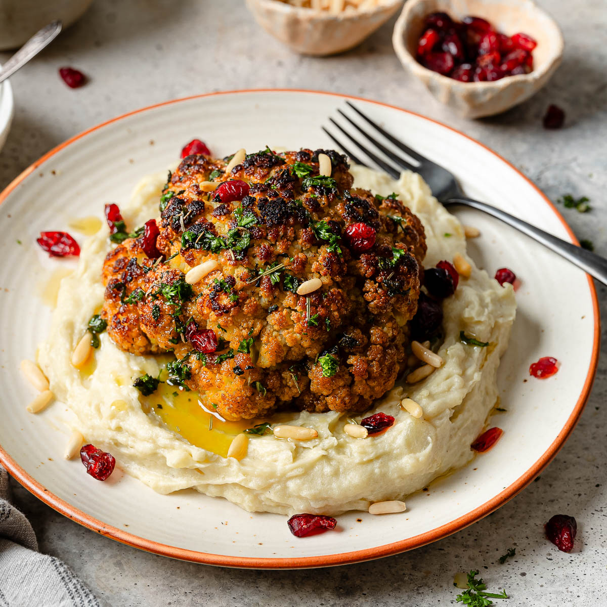A whole roasted cauliflower head on a bed of mashed potatoes