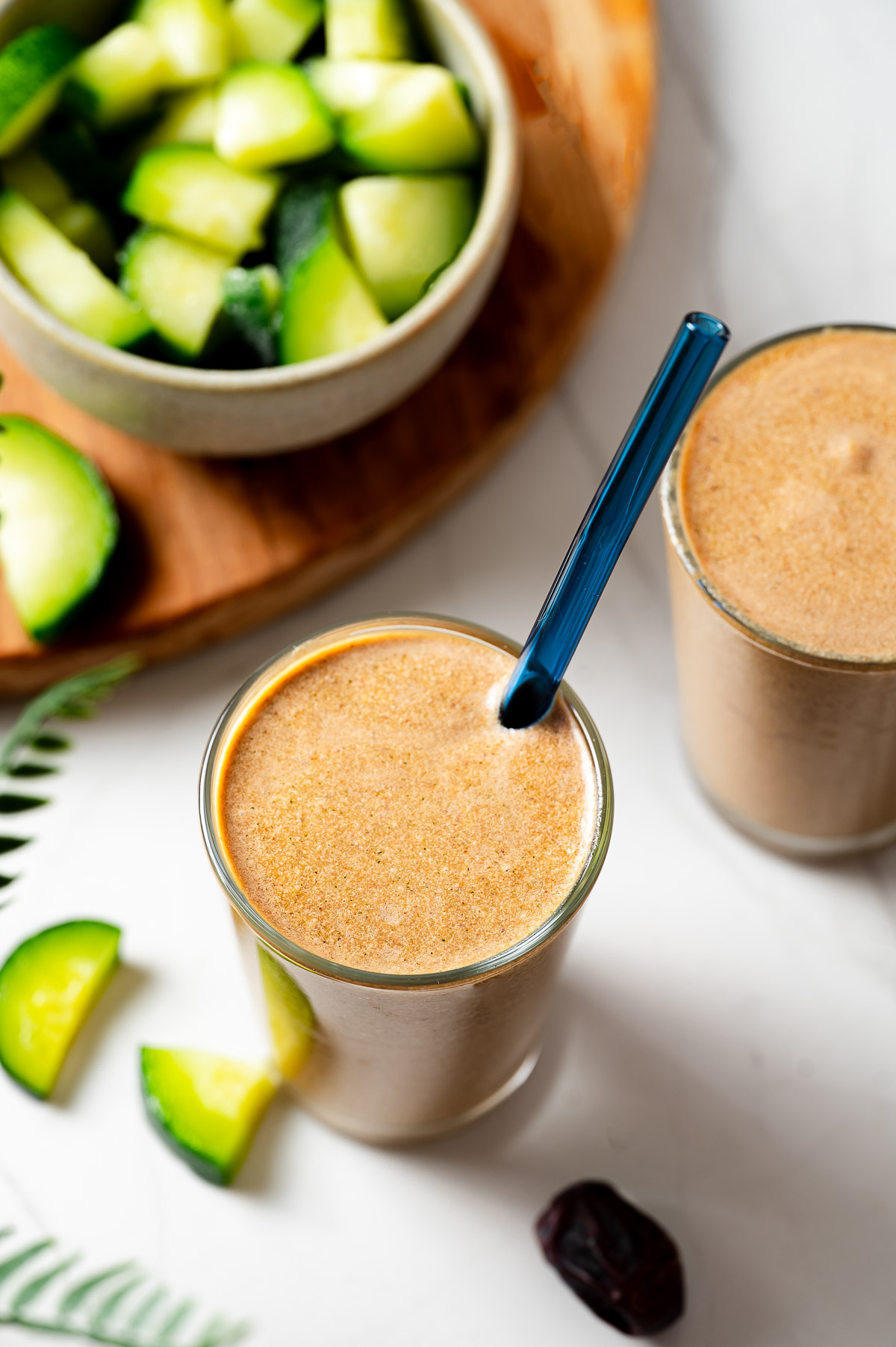 A glass of low calorie zucchini smoothie with a blue straw
