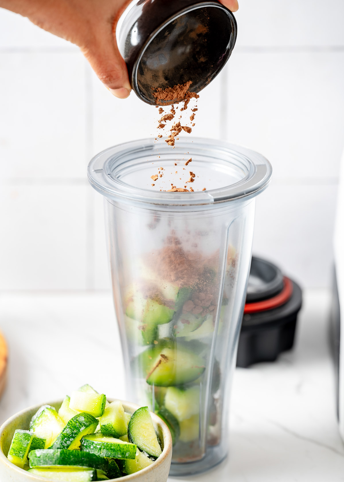 A person adding cacao powder into a blender