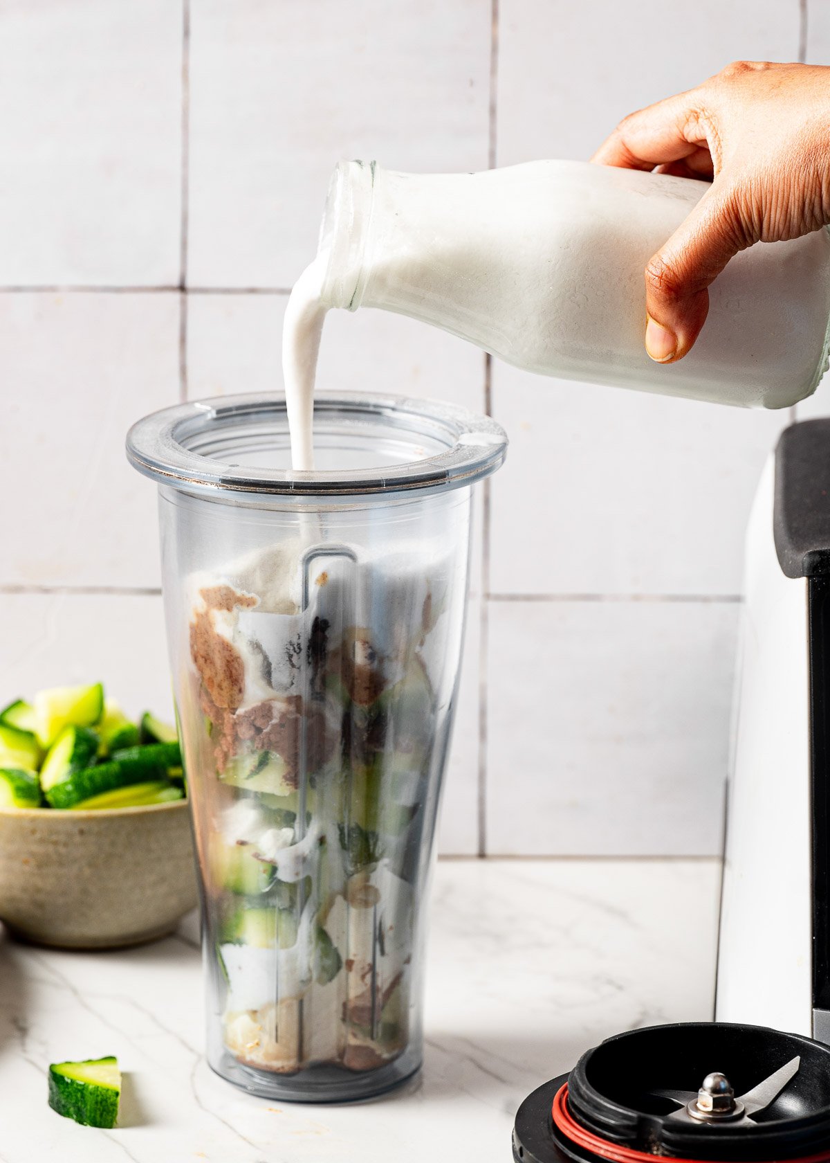 Cashew milk being poured from a glass jar into a blending container