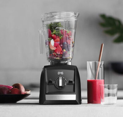 Modern kitchen with black blender next to a glass of red smoothie