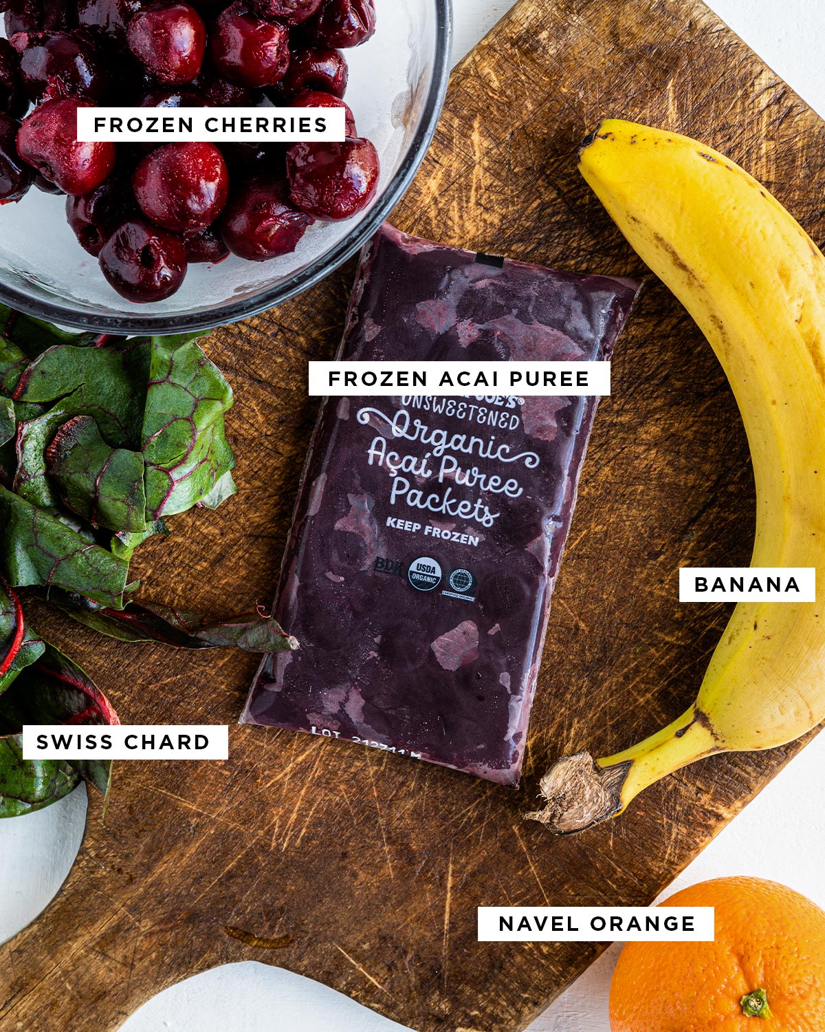 labeled ingredients including frozen cherries, frozen acai puree, banana, swiss chard and navel orange.