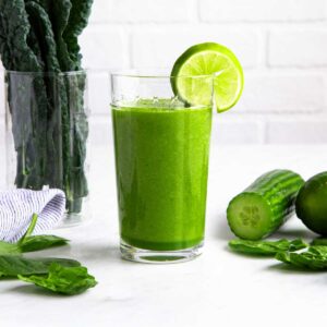 Alkaline smoothie in a tall glass with a lime wedge.