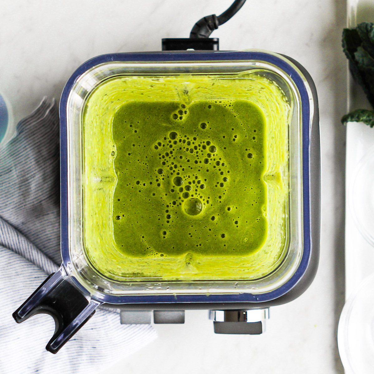 Blender with pureed kale and water to create a green liquid.