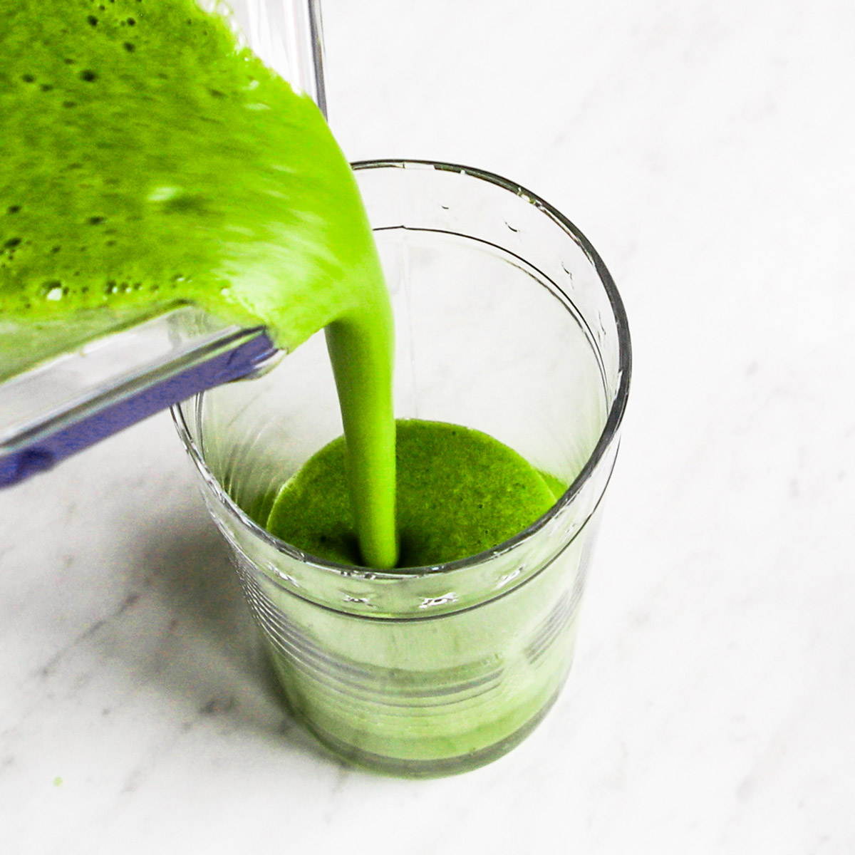 Pouring alkaline smoothie ingredients from blender into a glass.