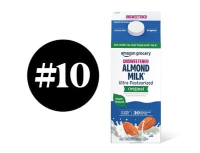Unsweetened almond milk carton with almonds and splash of milk.