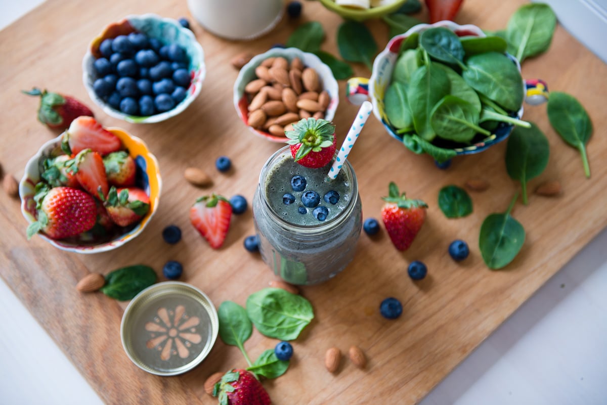 A glass of almond milk smoothie surrounded by ingredients