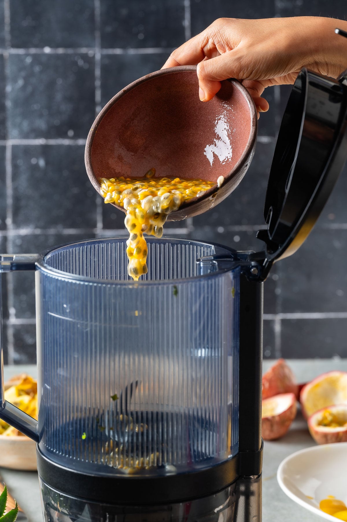 Pouring passionfruit pulp in a juicer
