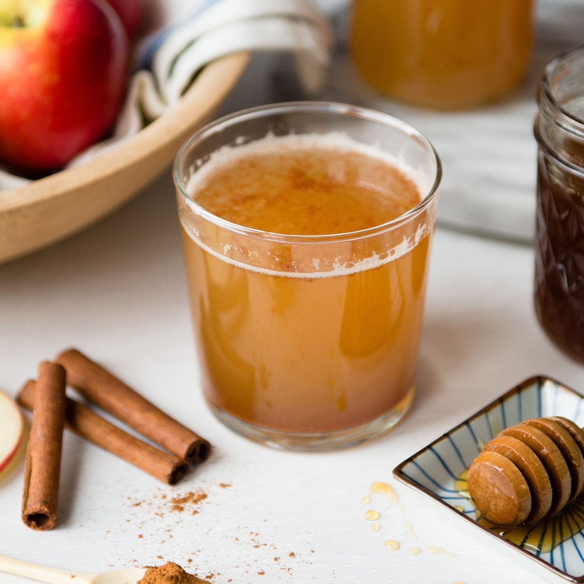 Apple cider vinegar drink in a small glass next to cinnamon sticks.