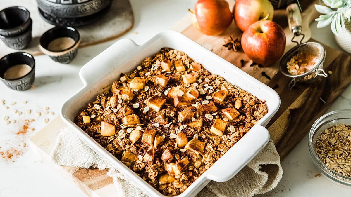 Baked oatmeal with cinnamon and apple chunks in a white dish.