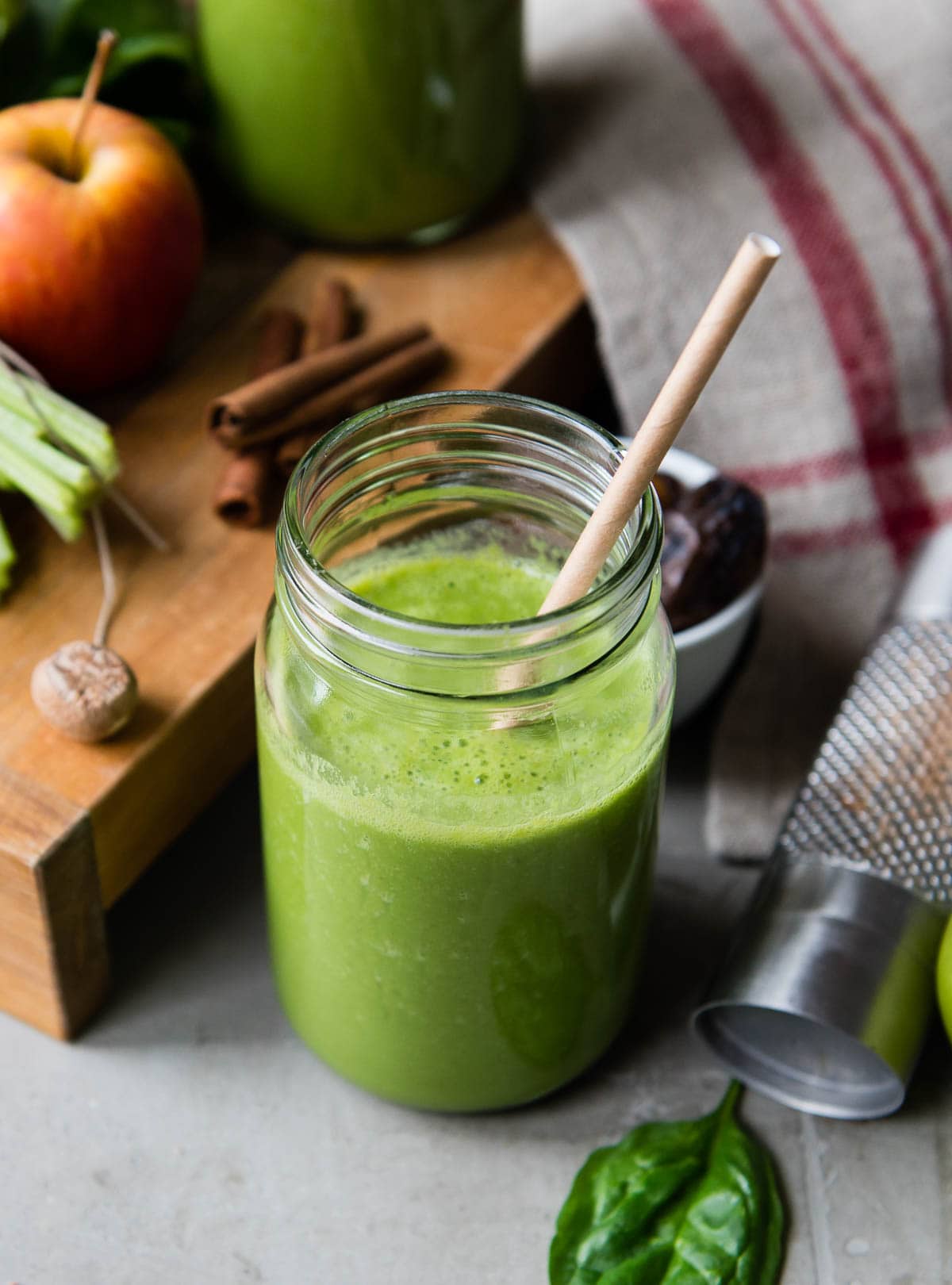 green smoothie in glass jar with paper straw.