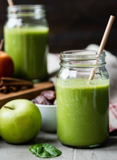 glass jar of warm apple pie smoothie surrounded by fresh ingredients.