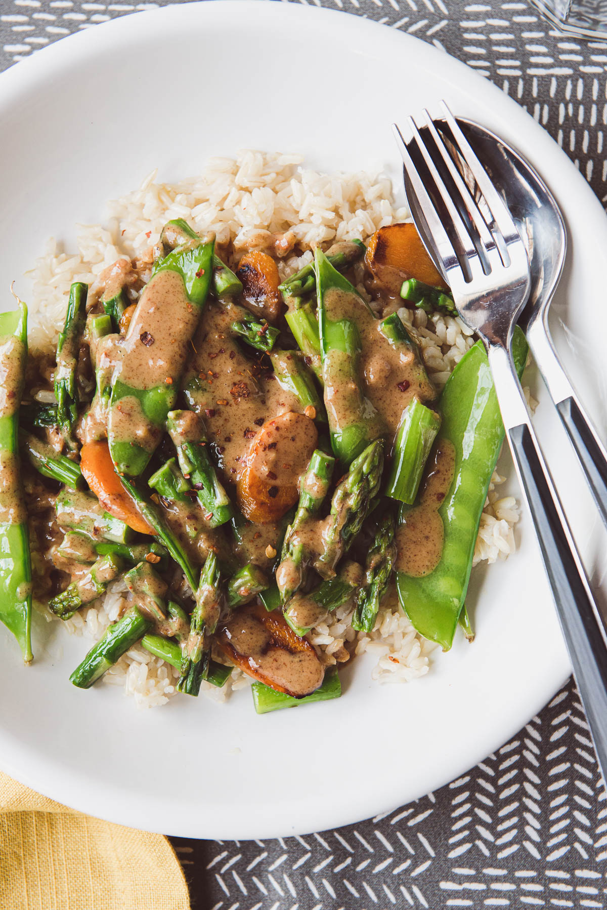 spring vegetable stir-fry covered with almond butter sauce on a bed of brown rice.