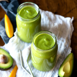 Glasses of avocado banana smoothie on table.