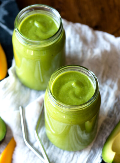 Glasses of avocado banana smoothie on table.