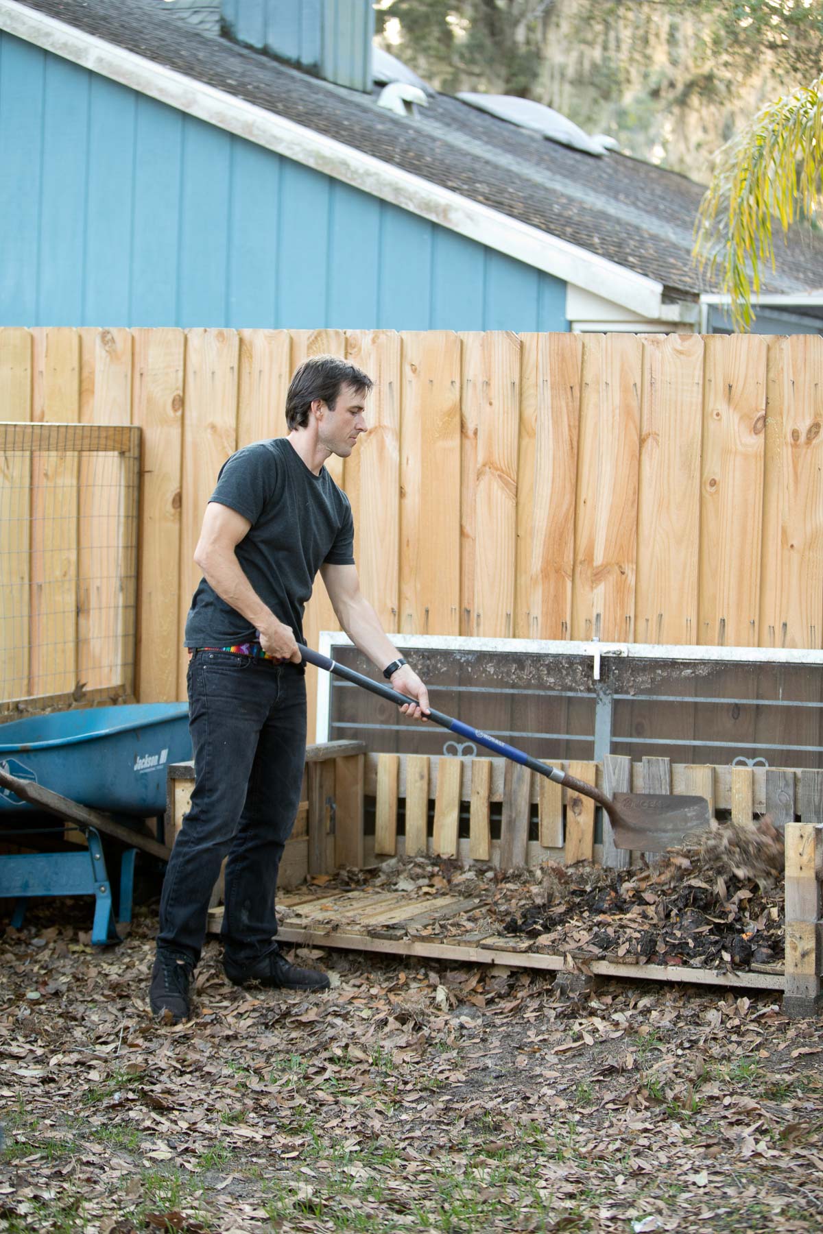 A man using a shovel to turn compost.