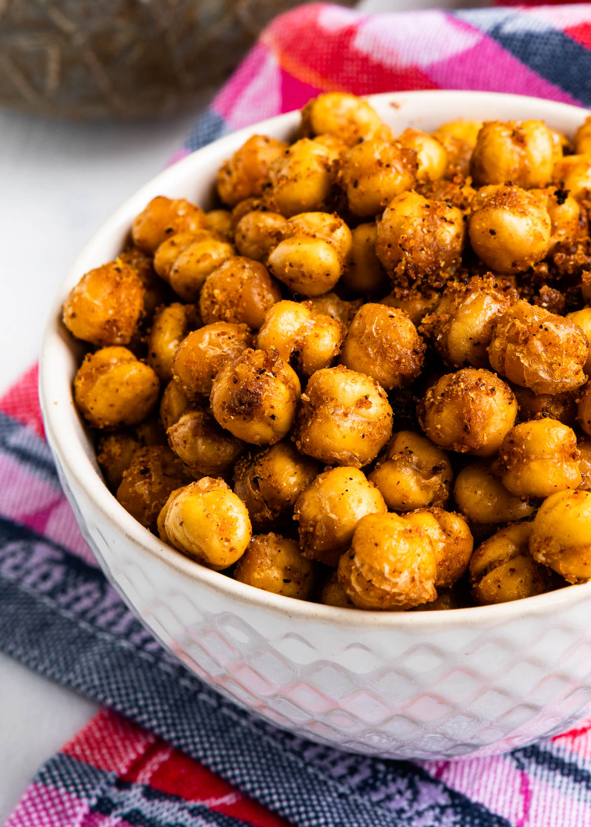 white bowl of crispy baked garbanzo beans with seasoning on them.