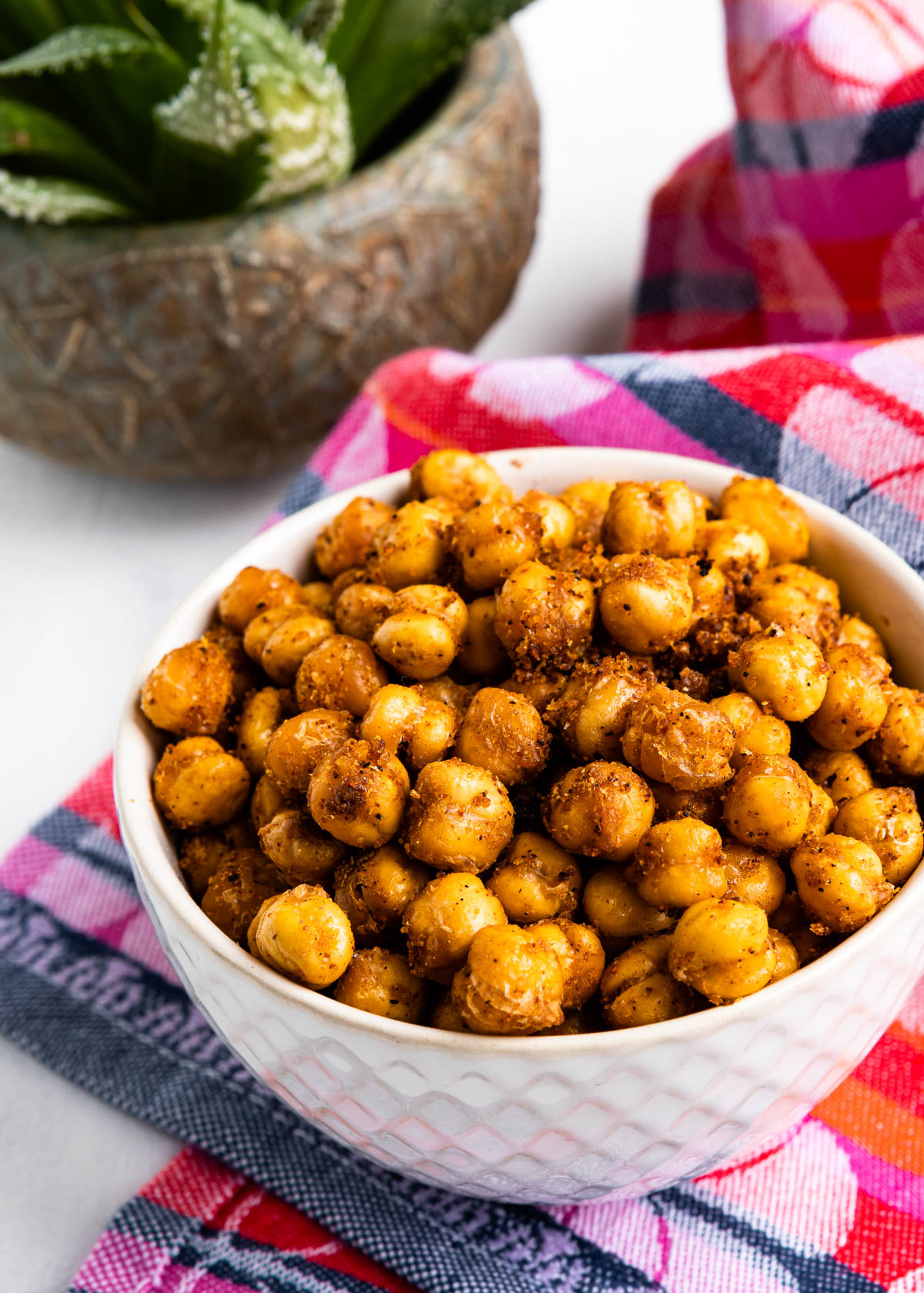 white bowl of crispy baked garbanzo beans with seasoning on them.