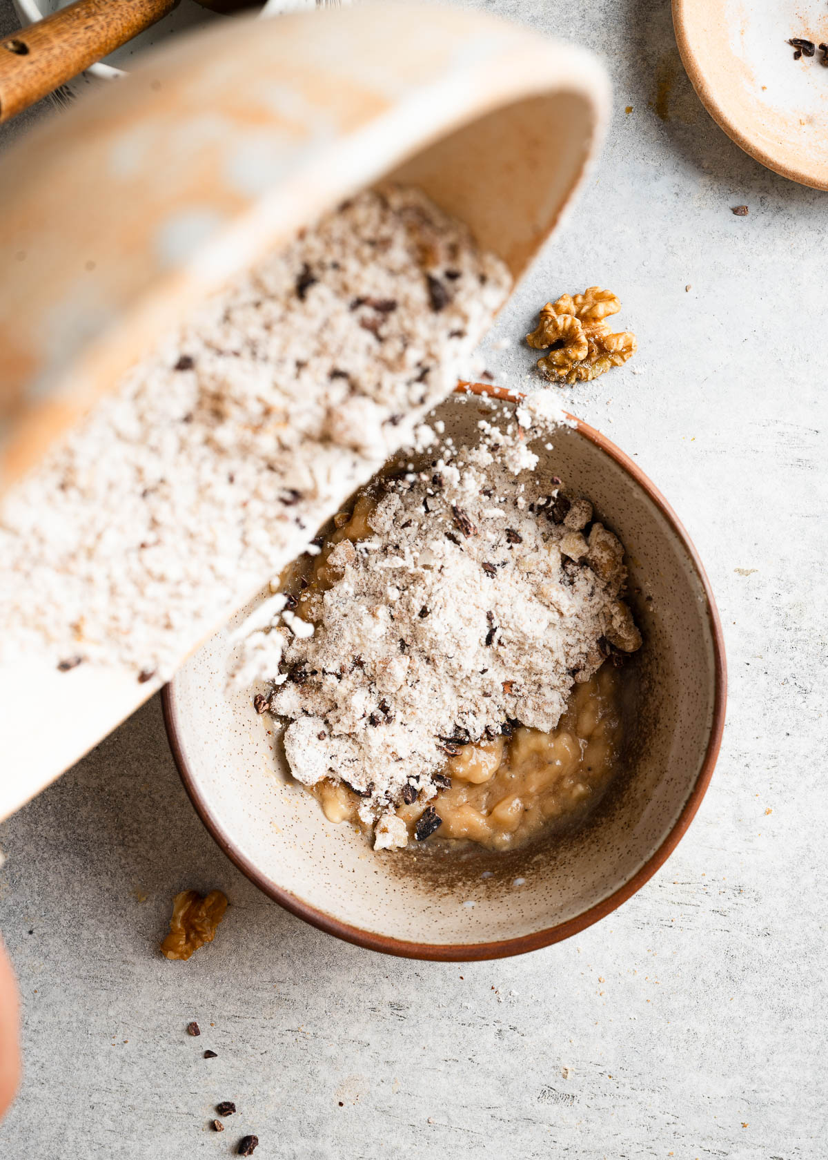 Flour being poured from a speckled container into a bowl for banana mug cake.