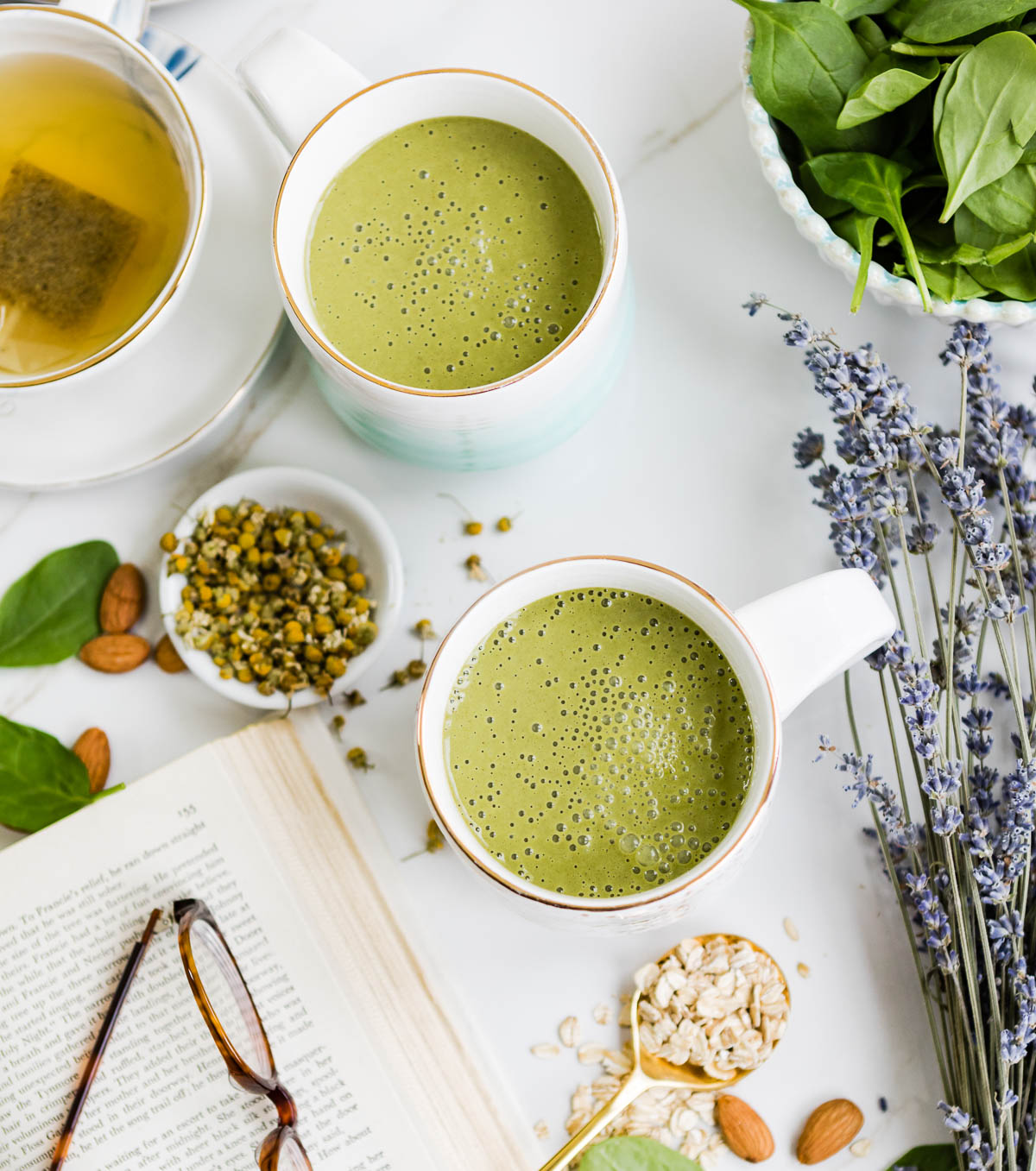 2 mugs of green bedtime smoothie surrounded by lavender, spinach and almonds.