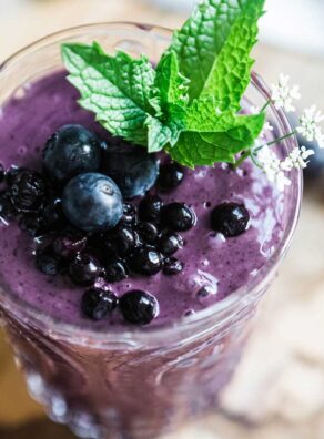 Berry smoothie in glass with fresh blueberries on top