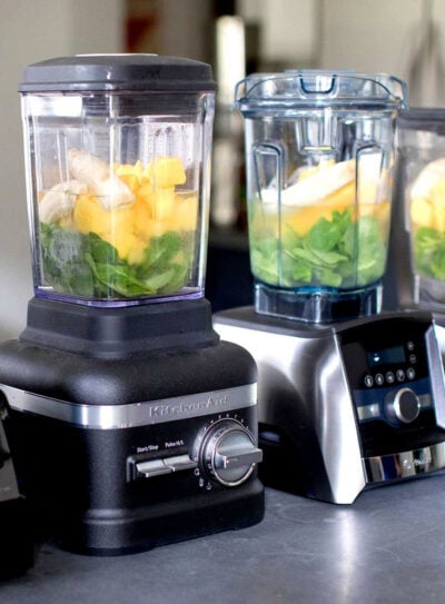 variety of blenders in a row with smoothie ingredients