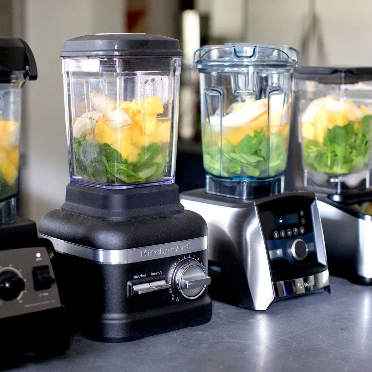 variety of blenders in a row with smoothie ingredients