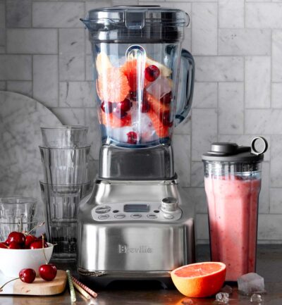 breville blender on gray counter with cherries and pink straws.