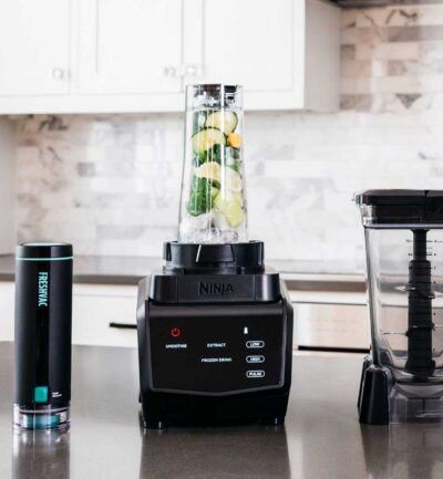 black ninja blender in modern kitchen with white cabinets.