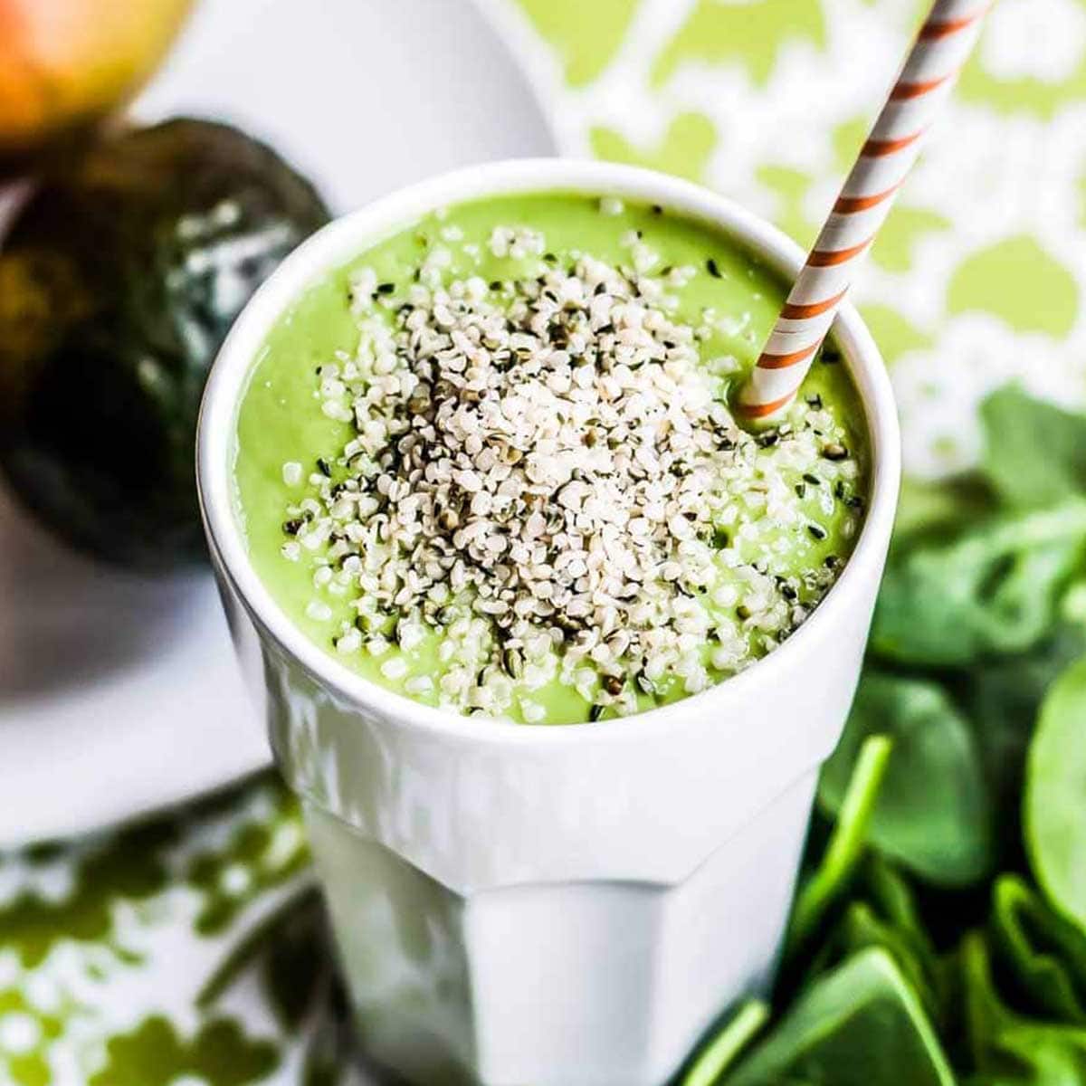 best brain food smoothie in white glass topped with hemp hearts and a paper straw.