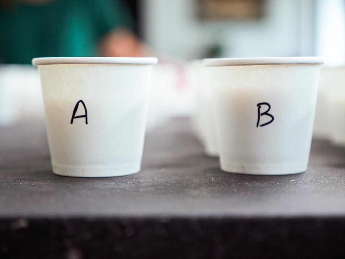 2 small white paper cups one labeled A and one labeled B, ready for a taste test.