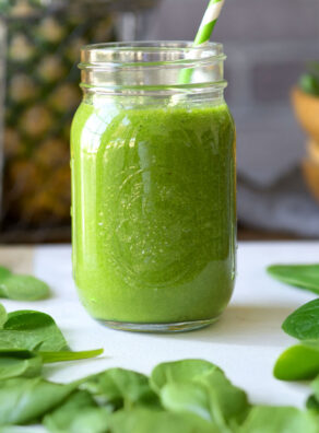 Green and white striped straw in a jar of green smoothie.