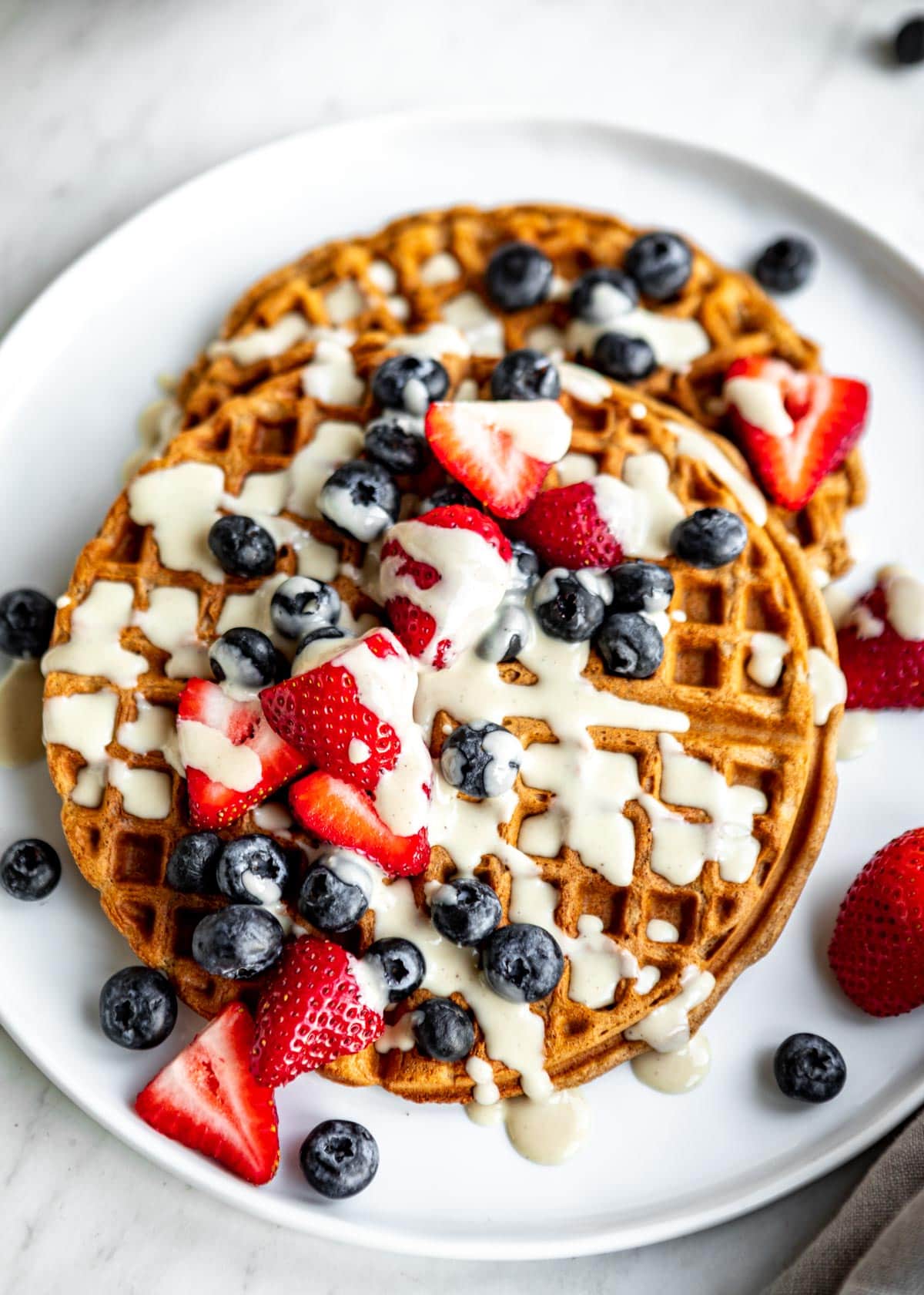 homemade vegan waffles topped with coconut whipped cream and fresh berries.