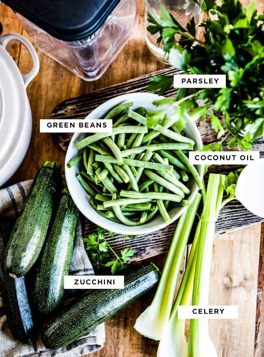 ingredients for a delicious blended vegetable soup including parsley, green beans, coconut oil, zucchini and celery.