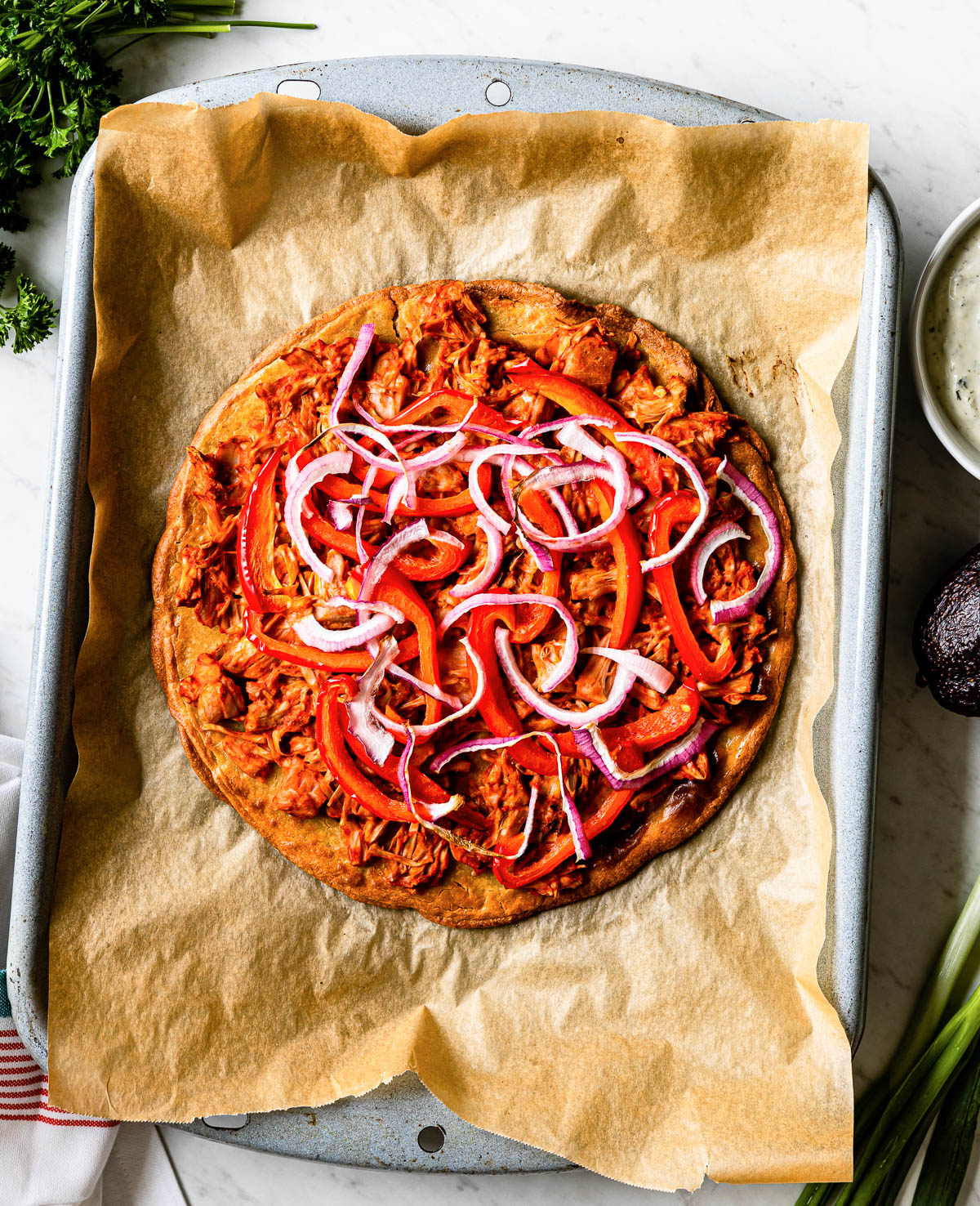 adding fresh bell pepper and red onions to the top of a cooked pizza crust.