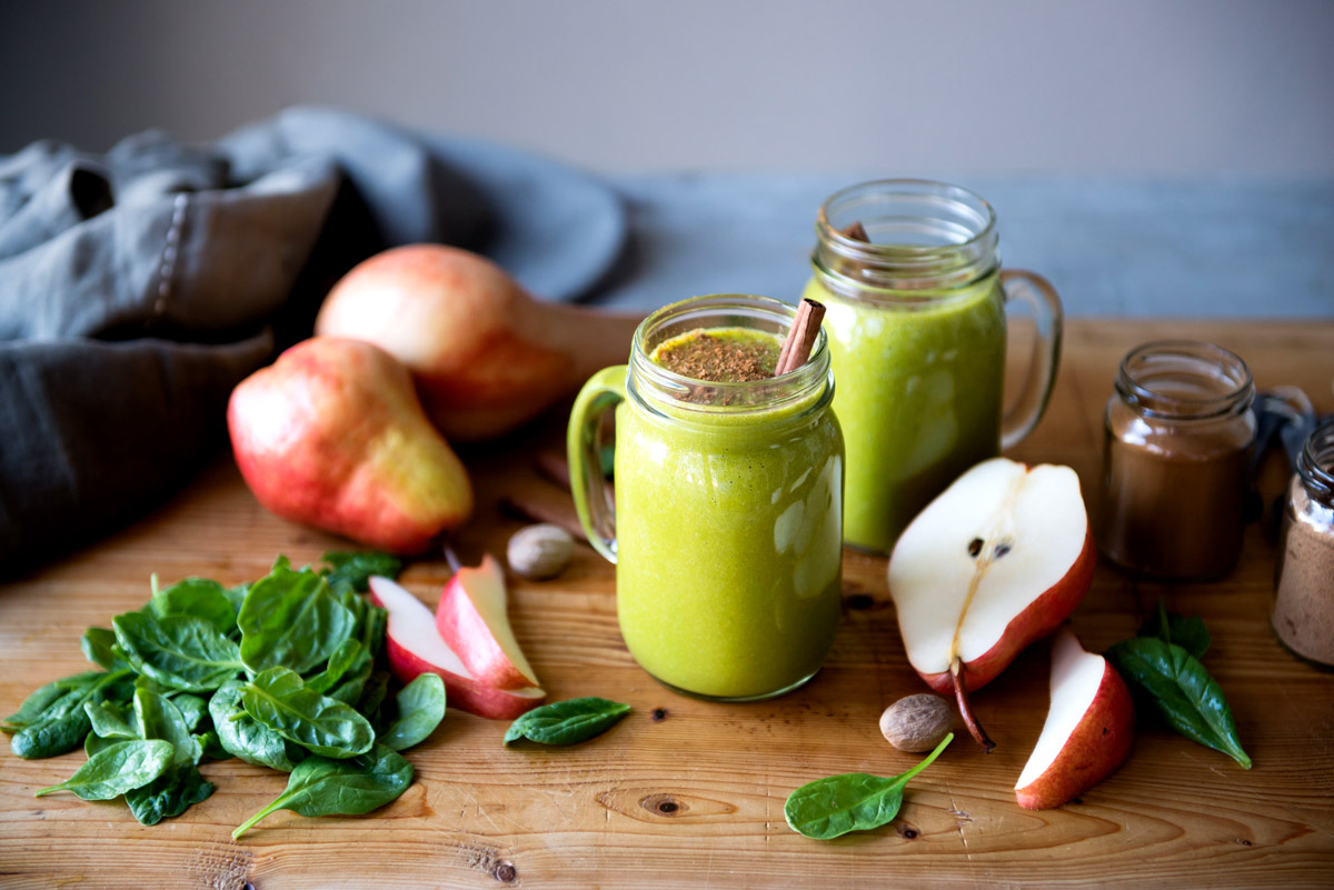 butternut squash smoothie in a glass mug with a cinnamon stick sticking out of the top.