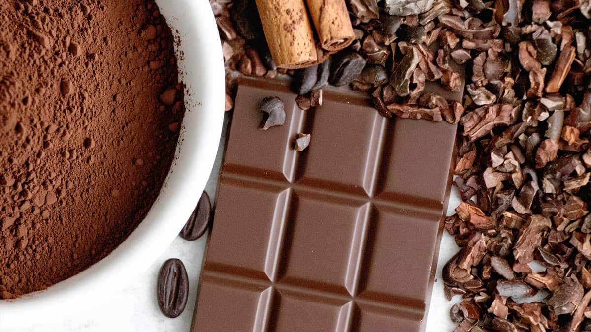 Assorted chocolate pieces, cocoa powder, and cacao nibs for dessert recipes.