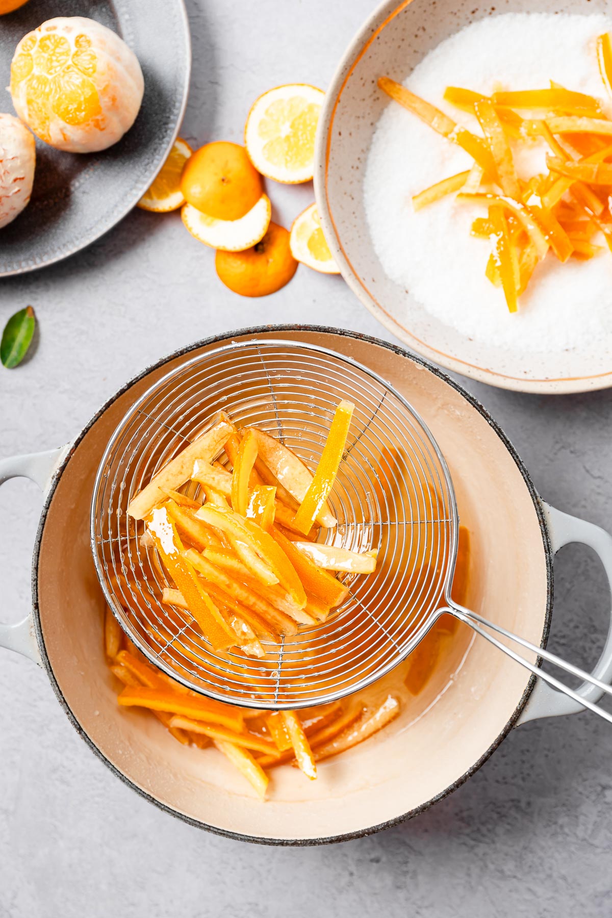Bright orange peels drained from simmering sugar syrup